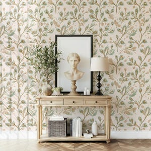 May include: A light wood console table with three drawers and a white bust sculpture on top. The table is in front of a wall with a beige and green floral wallpaper pattern.