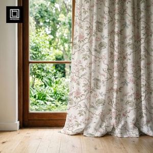 May include: A floor-length curtain featuring an off-white background with a repeating pattern of pink flowers, green leaves, and long-necked birds perched on thin branches. The fabric hangs in soft vertical folds, covering part of a window frame.