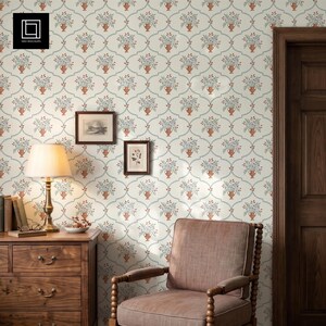 Peut inclure: Papier peint avec un motif répétitif d'urnes couleur terre cuite remplies de compositions florales bleues et vertes, sur un fond crème avec des lignes courbes bleu clair. Une commode en bois, une lampe et un fauteuil sont placés devant.
