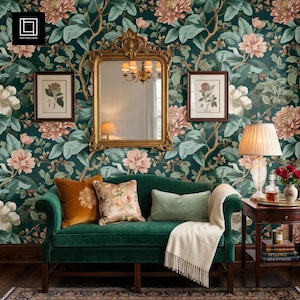May include: A living room scene featuring a green velvet sofa with decorative pillows and a cream-colored throw blanket. The wall is adorned with floral wallpaper in shades of green, pink, and white, with a gold-framed mirror and artwork.