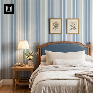 Peut inclure: Une chambre avec un papier peint à rayures bleues et blanches, une table de chevet en bois avec une lampe et un petit vase de fleurs, et un lit doté d'une tête de lit bleue, d'oreillers blancs et d'un couvre-lit matelassé clair.