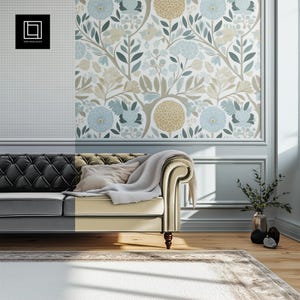 May include: A cream-colored sofa with a black leather back and arms, a white throw blanket, and a white pillow. The sofa is in front of a wall with a floral wallpaper pattern in shades of blue, green, and yellow.