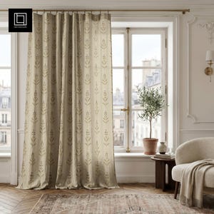 May include: A floor-length beige curtain featuring a repeating vertical pattern of olive green botanical sprigs. The curtain hangs from a simple metal rod with rings, displaying a soft drape and a light-filtering texture that covers a window.