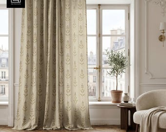 Puede incluir: Una cortina beige de cuerpo entero con un patrón vertical repetitivo de ramas botánicas de color verde oliva. La cortina cuelga de una sencilla barra de metal con anillas, mostrando una caída suave y una textura que filtra la luz.