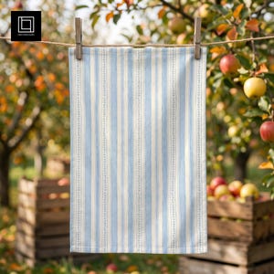 May include: A rectangular kitchen towel featuring a vertical striped pattern in light blue and off-white. The design includes thin, delicate leaf-like vine motifs running vertically between the wider blue stripes, creating a balanced, repeating pattern.