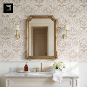 May include: A bathroom scene featuring a gold-framed mirror, sconces, and a marble countertop with a sink and faucet. The wallpaper has a beige and white floral pattern. A soap dispenser and flowers are on the counter.