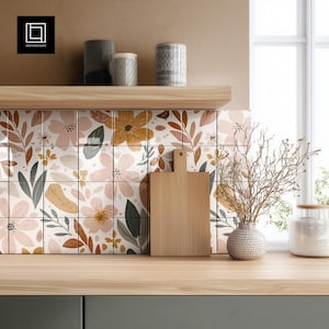 May include: A kitchen scene featuring floral patterned tiles, a wooden cutting board, and a vase with dried branches. The tiles have a white background with pink, yellow, and brown floral designs. A wooden shelf holds decorative canisters.