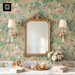 Peut inclure: Une coiffeuse de salle de bain avec un miroir doré, des appliques murales et une tapisserie florale en arrière-plan. La coiffeuse comprend un comptoir en marbre avec un plateau de flacons de parfum, une bougie et un vase de fleurs. Des serviettes et un robinet sont également visibles.
