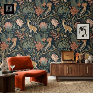 May include: A room featuring a dark blue floral wallpaper with deer and bird illustrations. An orange chair and wooden cabinet with a record player are in the foreground. A framed abstract art piece hangs on the wall.