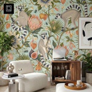 May include: A room with a light blue wallpaper featuring lemurs, flowers, and fruit. A white armchair, a small round table, and a wooden cabinet with a record player are in the room. A framed abstract art piece hangs on the wall.