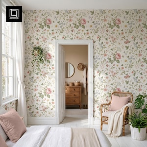 May include: A bedroom scene featuring floral wallpaper with pink roses and green foliage. A wicker chair with a pink pillow and a white blanket sits near a window with white curtains. A bed with a white comforter and pink pillows is in the foreground.