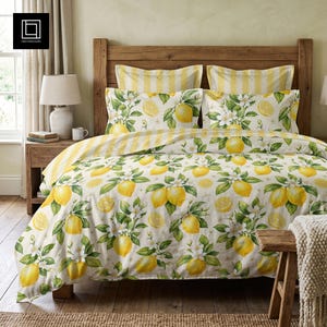 May include: A bedding set featuring a white duvet cover and pillowcases decorated with a repeating pattern of yellow lemons, green leaves, and white blossoms. The top edge of the bedding displays a yellow and white vertical striped fabric pattern.
