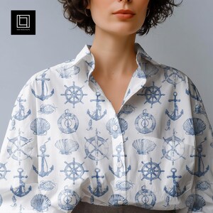 Könnte beinhalten: Ein weißes, langärmeliges Hemd mit Knopfleiste und einem sich wiederholenden nautischen Druck in Blau. Das Muster besteht aus detaillierten Illustrationen von Schiffsankern, Steuerrädern und verschiedenen Muscheln auf dem Stoff.