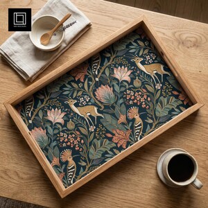 Può includere: Un vassoio da portata rettangolare in legno con uno sfondo blu navy scuro e un motivo ripetuto di gazzelle marrone chiaro, uccelli crestati, fiori rosa e fogliame verde. Il vassoio è accompagnato da una ciotola bianca, un cucchiaio di legno e una tazza.