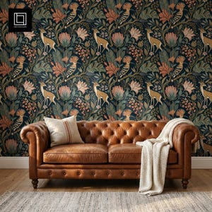 May include: A brown leather tufted sofa with rolled arms, featuring a cream-colored throw blanket and a matching pillow with a vertical stripe. The background is wallpaper with a repeating pattern of birds, deer, and flowers in muted tones.