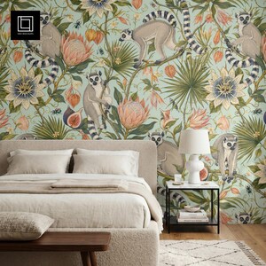 Peut inclure: Une chambre avec un lit et du papier peint à motifs. Le papier peint a un fond bleu clair avec des illustrations de lémuriens, de fleurs et de feuillages. Une lampe blanche est posée sur une table de chevet noire. Un banc en bois et un tapis sont au premier plan.