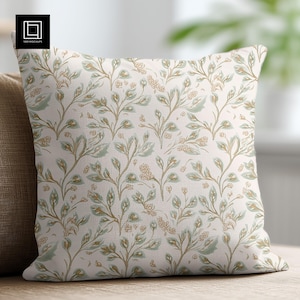 May include: A white throw pillow with a floral pattern in shades of green and brown. The pillow has a subtle texture and a soft, comfortable feel.