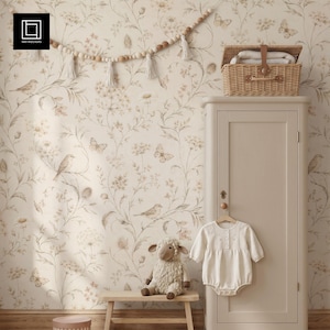 Pode incluir: Uma cena de berçário com papel de parede floral com pássaros e borboletas. Um pequeno banco de madeira contém um cordeiro de pelúcia. Um armário branco tem um body de bebê pendurado em um cabide de madeira.