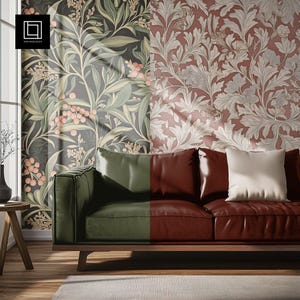 Op de afbeelding: Een groene en bruine behang met een bloemenpatroon met een rode leren bank met drie kussens. De bank staat voor het behang en de kamer heeft een houten vloer.