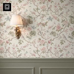 May include: A wall lamp with a pleated white shade and a brass-toned base mounted on a wall covered in cream-colored wallpaper featuring a repeating pattern of pink flowers, green leaves, and white birds perched on brown branches above a green wainscot.