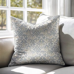 May include: A decorative throw pillow with a white background and a blue and beige damask pattern.