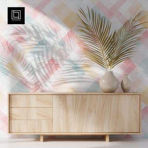 Op de afbeelding: Een licht houten kast met drie lades en een deur. Twee beige vazen ​​bevatten gouden palmbladeren. De achtergrond heeft een pastelkleurig ruitpatroon met schaduwen van palmbladeren. Het logo "1001 Mockups" staat linksboven.