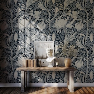May include: A dark blue wallpaper with a white floral pattern. A wooden console table with a white bust, books, and a vase with dried flowers sits in front of the wallpaper.