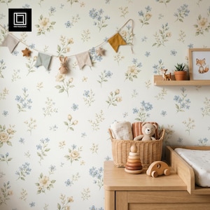 May include: A nursery scene with floral wallpaper in cream, yellow, and blue. A wooden changing table holds a woven basket with a teddy bear, blankets, and a wooden toy. A garland with felt shapes hangs above.