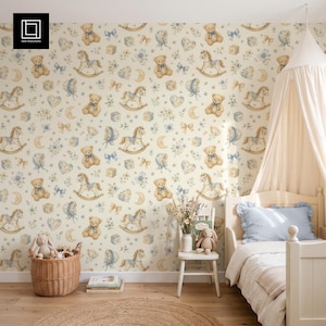 Könnte beinhalten: Tapete mit einem wiederkehrenden Muster aus Teddybären, Schaukelpferden, Mondsicheln, Herzen und Schleifen in sanften Blau- und Beigetönen. Das Design enthält kleine florale Akzente und Spielwürfel auf einem hellen cremefarbenen Hintergrund.