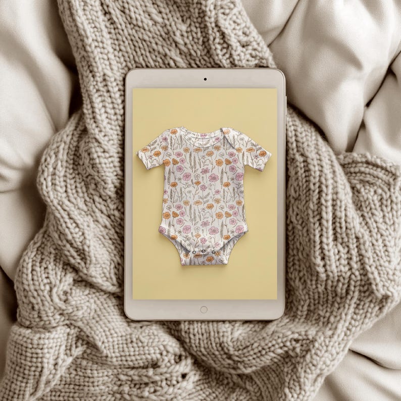 May include: A white baby onesie with a floral print on a yellow background displayed on a tablet screen.