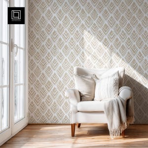 Könnte beinhalten: Gemütliche Inneneinrichtung mit weißem Sessel, Kissen und Decke. Die Wand ist mit einem sich wiederholenden beigen Blattmuster verziert. Ein Fenster mit natürlichem Licht und Holzboden vervollständigen das Bild.
