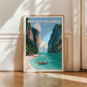 Può includere: Un poster da viaggio incorniciato delle isole Phi Phi in Thailandia. L'illustrazione raffigura imponenti scogliere calcaree, acqua turchese, una spiaggia sabbiosa e una barca tradizionale. Il testo recita PHI PHI ISLANDS THAILAND.