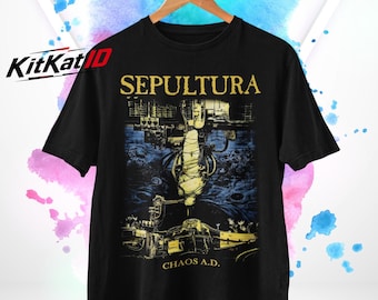 Puede incluir: Una camiseta negra de manga corta con un estampado gráfico que incluye el texto SEPULTURA y CHAOS A.D. en amarillo. La ilustración central muestra una escena mecánica oscura con una figura envuelta en tela blanca sobre un fondo azul.