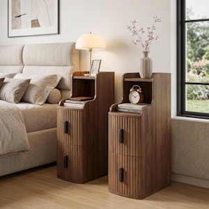 May include: Two tall, narrow bedside tables made of dark wood with a vertical fluted texture on the front. Each table features two drawers with long, rectangular black handles and an open shelf at the top for storage and display purposes.