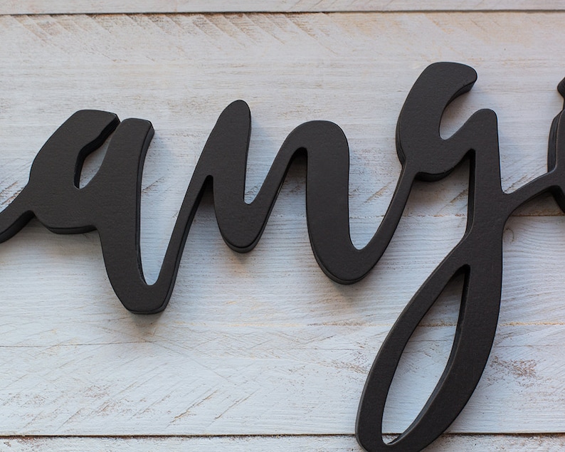 May include: Black wooden sign with the word "rang" written in a cursive font.