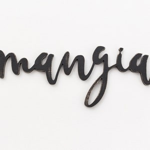 May include: Black wooden sign with the word "mangia" written in cursive script.