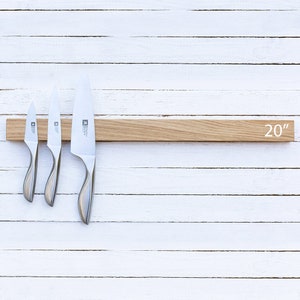 May include: A 20-inch wooden magnetic knife holder with three silver knives attached. The holder is made of light brown wood and has a white background.