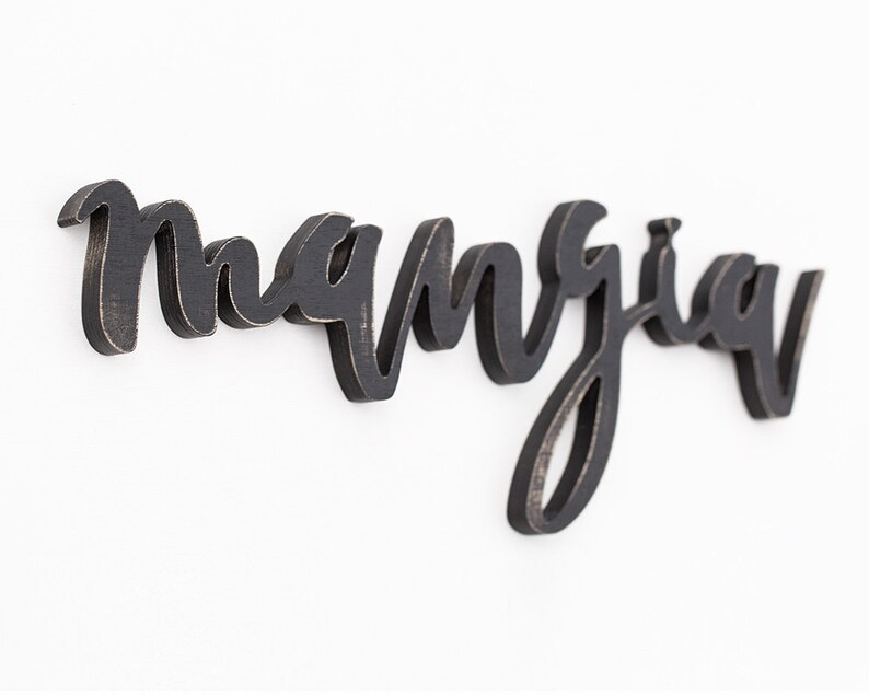 May include: Black wooden sign with the word "manjua" written in cursive script.