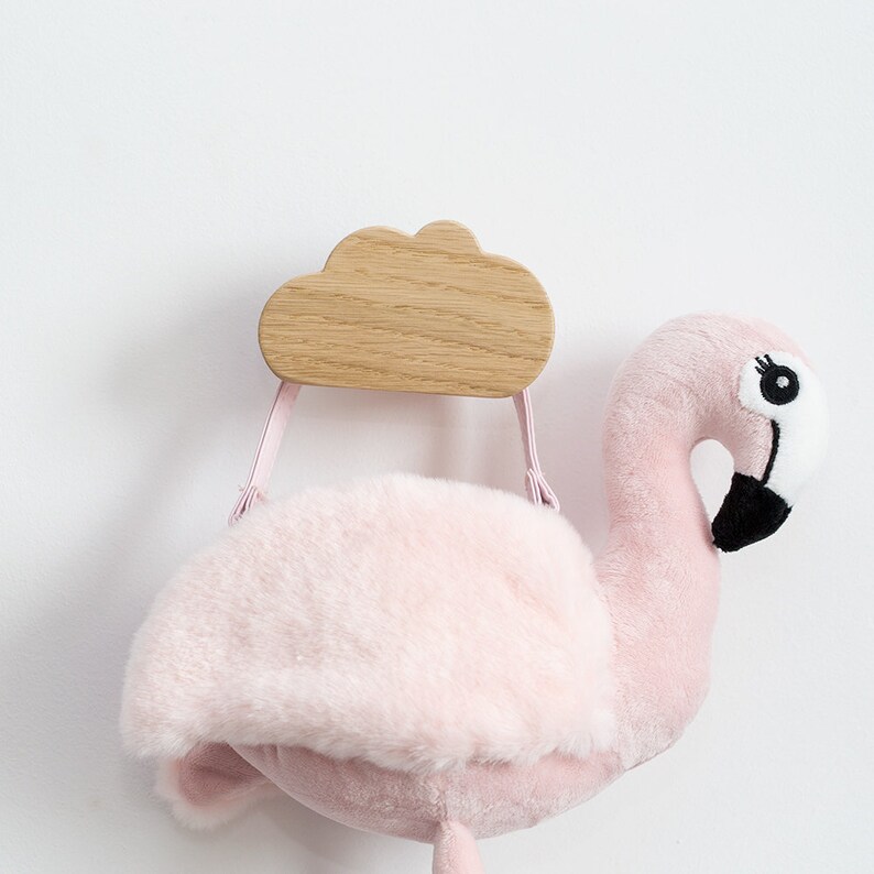 May include: Pink plush flamingo toy with a wooden cloud shaped hook attached to its back. The hook has two pink straps.
