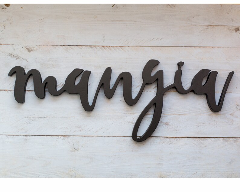 May include: Black wooden sign with the word "mangia" written in cursive script.