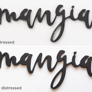 May include: Two wooden signs with the word "mangia" written in black script. The top sign has a distressed finish, while the bottom sign has a smooth, black finish.