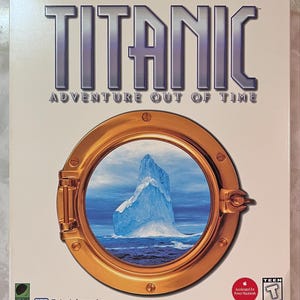 May include: A rectangular game box for Titanic Adventure Out of Time featuring a large gold-colored circular porthole in the center. Through the porthole, a blue iceberg is visible in the ocean. The title text is printed in large silver letters.
