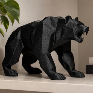 Könnte beinhalten: Eine schwarze Bärenfigur mit einer geometrischen, facettierten Oberflächenstruktur. Der Bär ist in einer stehenden, nach vorne gerichteten Pose dargestellt, mit geöffnetem Maul und sichtbaren Zähnen. Die Skulptur weist scharfe, kantige Flächen auf.