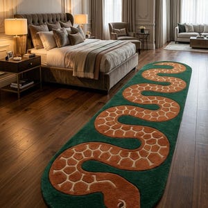 May include: An elongated oval area rug featuring a deep green background with a large, winding orange snake motif. The snake has a textured, scale-like pattern in a lighter cream colour across its body and a forked tongue extending from its head.