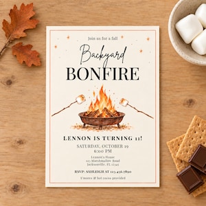 May include: A rectangular invitation card featuring a watercolour bonfire illustration with two marshmallows on sticks. Text reads: Join us for a fall Backyard BONFIRE, LENNON IS TURNING 11!, SATURDAY, OCTOBER 19, 6:00 PM, Lennon's House, 123 Marshmallow Road, Jacksonville, FL 12345, RSVP: ASHLEIGH AT 123.456.7890, S'mores & hot cocoa provided.