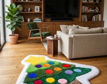 May include: A tufted area rug shaped like a Christmas tree with a white border, a yellow star topper, and colorful circular ornaments in red, blue, orange, purple, and pink. The tree has a brown trunk and is set against a white background.