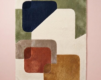 May include: A rectangular area rug featuring a geometric pattern of overlapping rounded shapes. The design incorporates blocks of cream, olive green, navy blue, terracotta, and mustard yellow, all rendered in a soft, plush, textured pile finish.