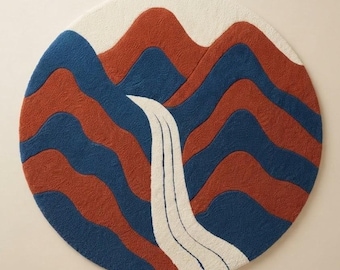 May include: A circular rug featuring a tufted landscape design with alternating wavy bands of deep blue and terracotta orange. A central white section depicts a flowing waterfall or stream that cuts through the mountain-like shapes.