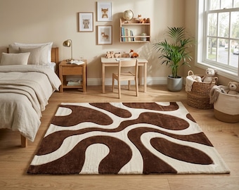 May include: A rectangular area rug featuring a high-contrast, abstract pattern of flowing, organic shapes in deep chocolate brown and creamy off-white. The rug has a thick, plush pile texture and is positioned centrally on a light wood floor.