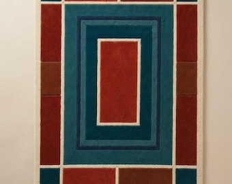 May include: A rectangular area rug featuring a geometric pattern of nested rectangles and blocks. The design consists of a central red rectangle surrounded by teal, dark blue, and cream borders, with outer blocks in red, brown, and teal colors.